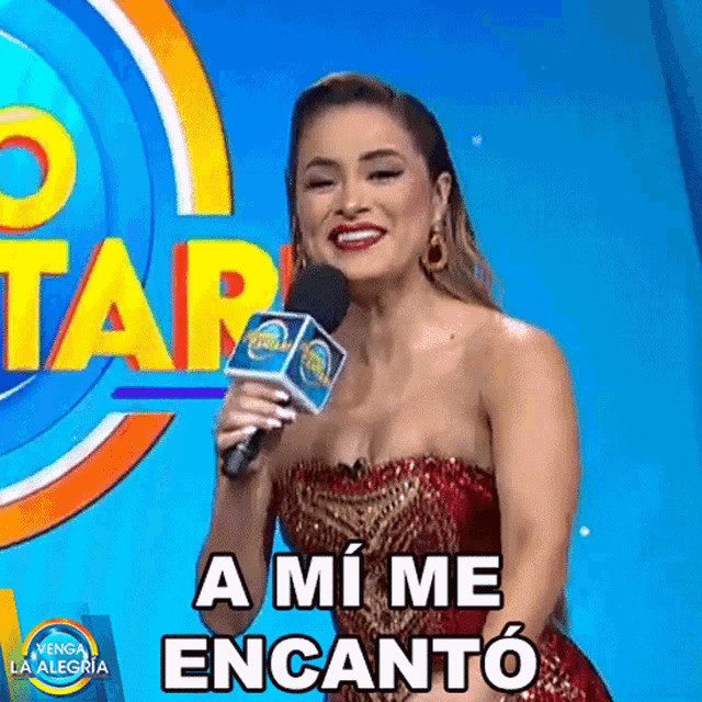 a woman in a red dress is holding a microphone and saying " a mi me encanto "