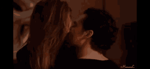 a man kissing a woman on the cheek in a dark room .
