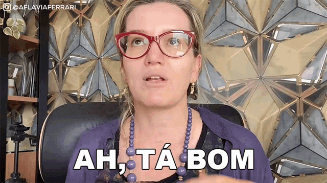 a woman wearing glasses is sitting in a chair and says ah ta bom