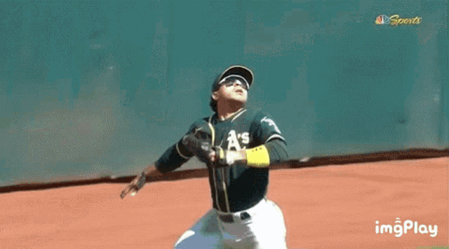 a baseball player is catching a ball in front of a stream banner