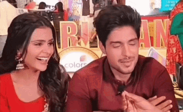 a man and a woman are sitting next to each other and laughing together .