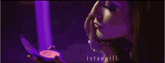 a woman is looking at herself in a mirror and the name istangili is on the bottom right