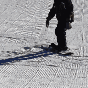 a person skiing down a snowy slope with a shadow on the snow