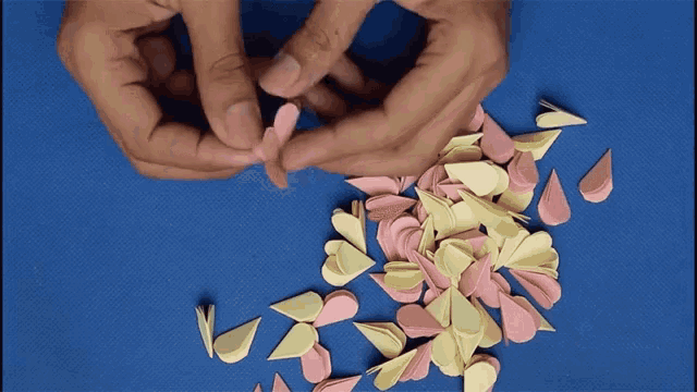 a person is making a flower out of paper petals