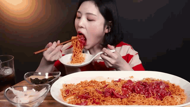 a woman is eating noodles with chopsticks from a bowl