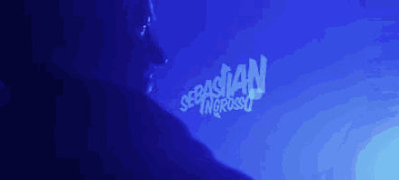 a man stands in front of a blue background that says sebastian ingrosso