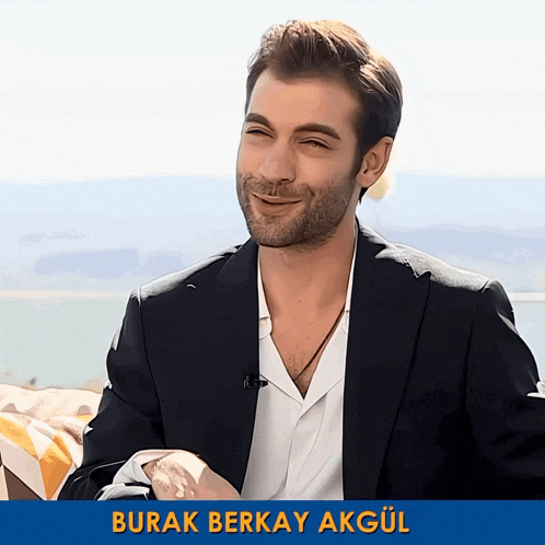 a man in a suit is smiling with the name burak berkay akgul below him