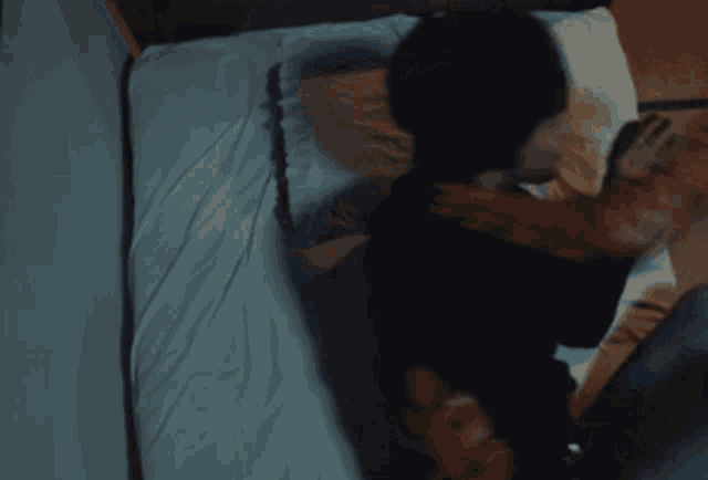 a person standing in front of a bed with a blue blanket