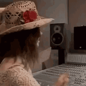 a woman wearing a hat is sitting in front of a sound board .