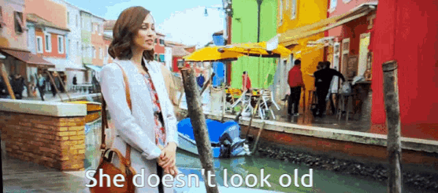 a woman is standing in front of a canal with the words she does n't look old