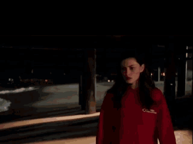 a woman in a red sweatshirt is standing in the dark .