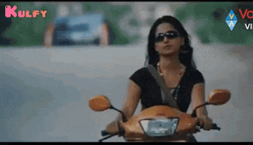 a woman is riding a motorcycle down a road .