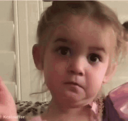 a little girl is making a funny face while sitting on a couch .