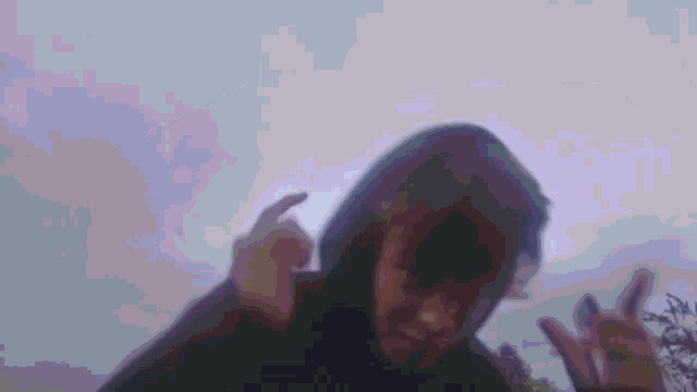 a blurry picture of a person in a hoodie giving the middle finger .
