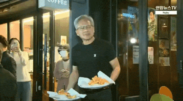 a man in a black shirt is carrying a tray of food in front of a coffee shop
