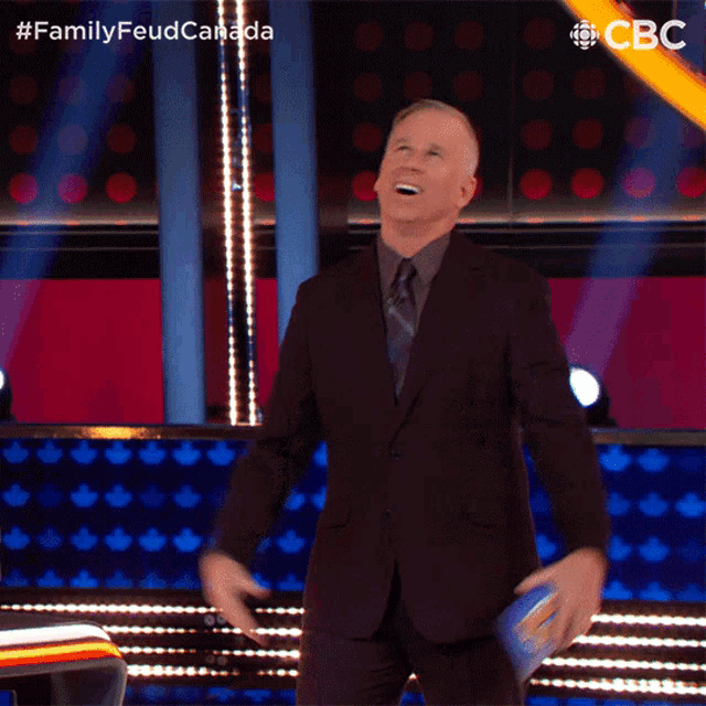 a man in a suit and tie is dancing on a stage with the hashtag familyfeudcanada