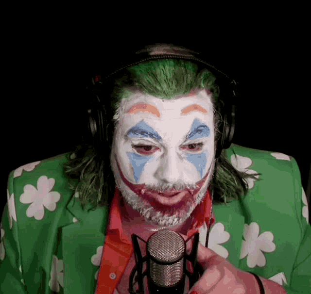 a man dressed as the joker is holding a microphone and wearing headphones