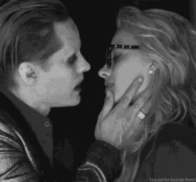 a black and white photo of a man and a woman kissing each other .