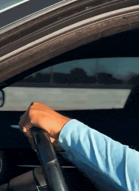 a person is holding the steering wheel of a car