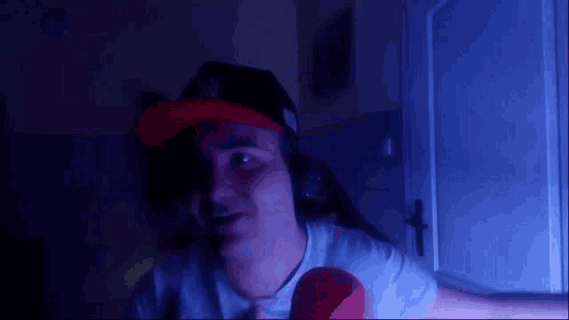 a man wearing a hat and headphones is holding a red ball