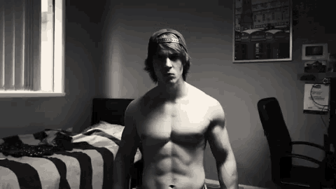 a shirtless man is standing in a room with a picture on the wall that says ' london '