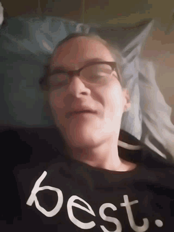 a woman wearing glasses and a black shirt that says best on it