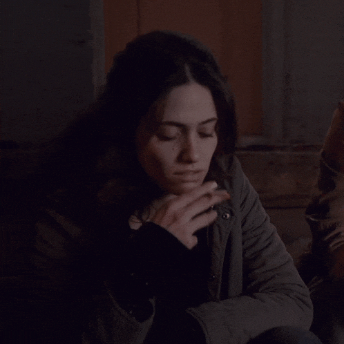 a woman blows a kiss while sitting in a dark room