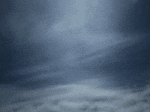 a dark cloudy sky with a few stars visible