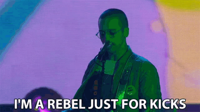 a man playing a guitar with the words " i 'm a rebel just for kicks " below him