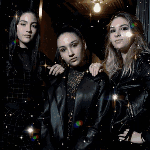 three girls are posing for a picture and they are all wearing black jackets