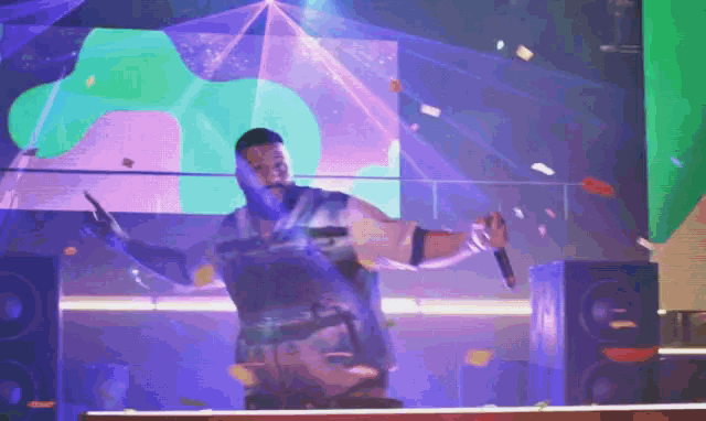 a man is holding a microphone in front of a purple and green background