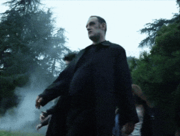 a man in a black coat is walking in a foggy forest