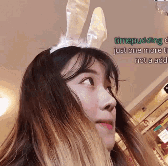 a woman wearing bunny ears is looking at the camera with the caption timepudding c just one more time not a add
