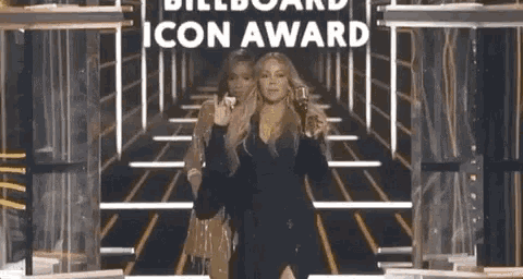 two women are standing on a stage in front of a sign that says billboard icon award