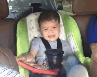 a baby is sitting in a car seat with a toy steering wheel .
