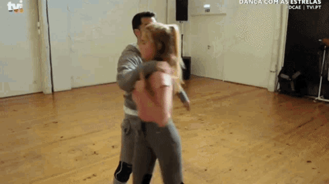 a man and a woman are dancing in a room with the tvi logo on the wall