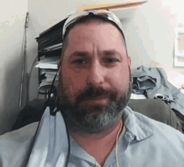 a man with a beard wearing sunglasses and headphones looks at the camera