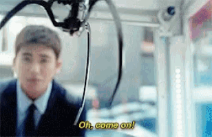 a man in a suit and tie is standing in front of a machine that says oh come on