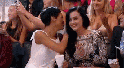 two women are sitting next to each other in a crowd .