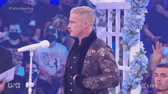 a man in a suit stands in front of a microphone with the index wedding written on the screen