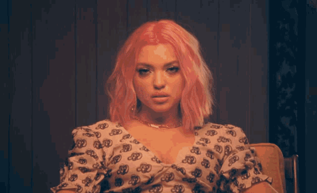 a woman with pink hair is wearing a necklace that says ' sd ' on it