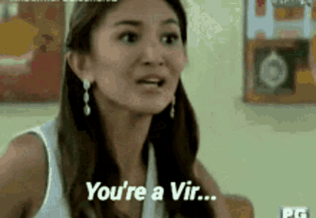 a woman in a white tank top is talking to another woman and says `` you 're a vir ... '' .