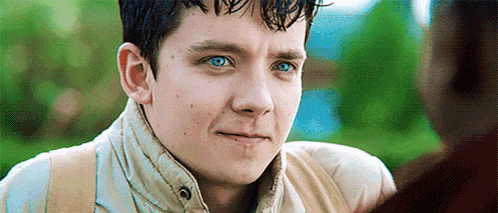 a close up of a young man with blue eyes looking at another man .