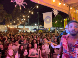 a man singing into a microphone in front of a crowd