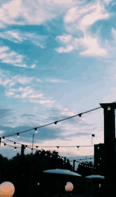 a string of lights hanging from a rooftop with a blue sky in the background