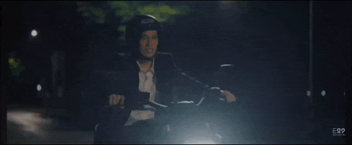 a man in a suit is riding a motorcycle at night .