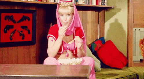 a woman is sitting at a table eating popcorn .