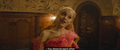 a woman in a pink dress is standing next to a man in a green suit who says you deserve each other