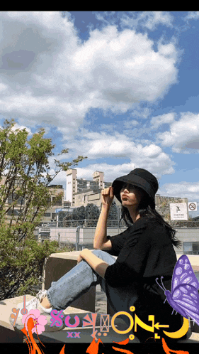 a woman wearing a black hat sits on a bench with a picture of a butterfly and the word soymon on it