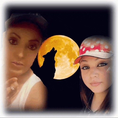 two women standing in front of a full moon with a wolf howling